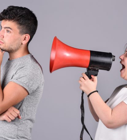 young girl shouting into megaphone at guy who can't hear